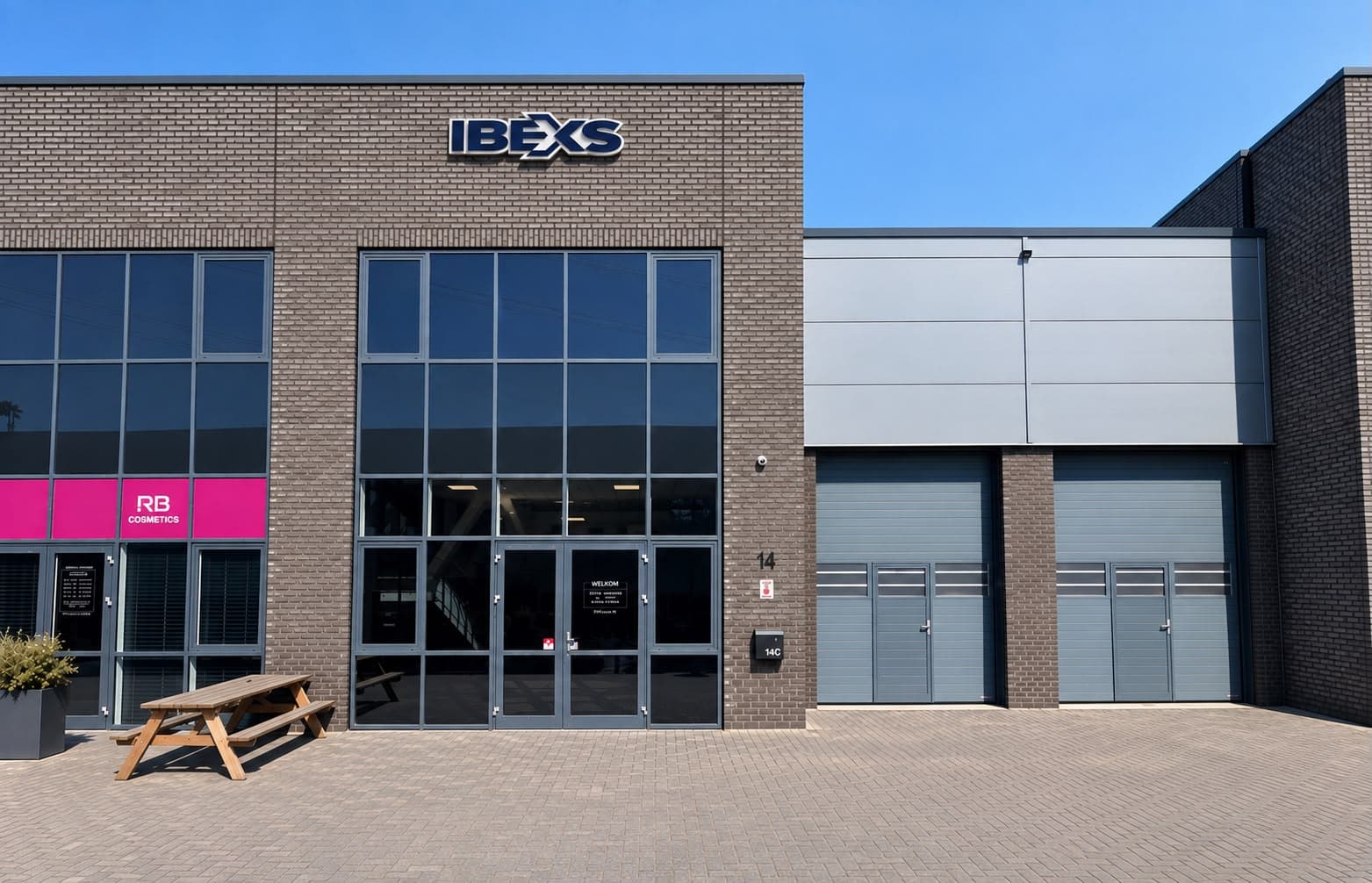 De gevel van het IBEXS-bedrijfspand met het IBEXS-logo en twee bedrijfsdeuren.